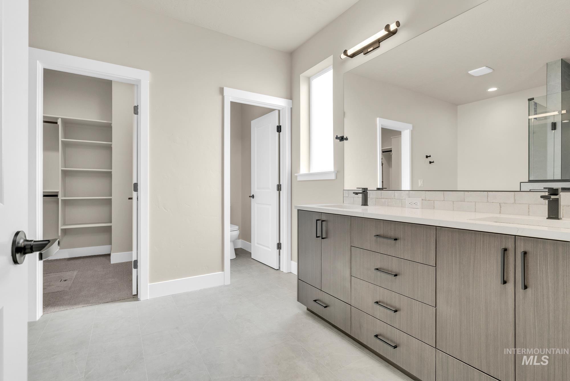 2848 West Jutland Street Meridian, ID 83642 - Photo 15 of 25 Full bathroom with a walk in closet, double vanity, backsplash, and a stall shower