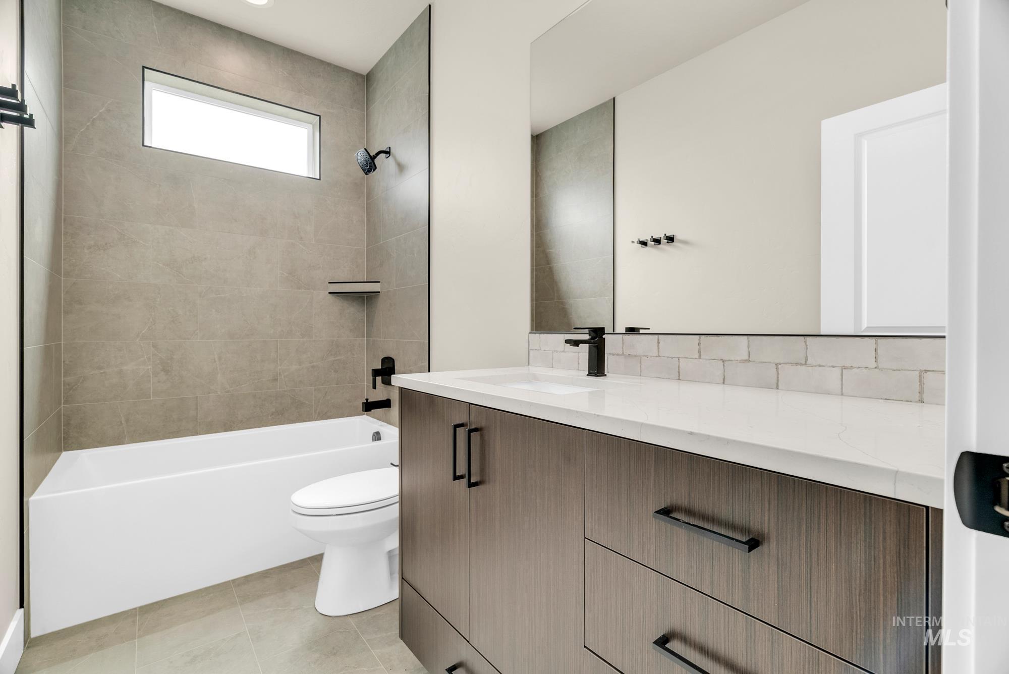 2848 West Jutland Street Meridian, ID 83642 - Photo 21 of 25 Bathroom with vanity, bathtub / shower combination, decorative backsplash, and light tile patterned floors