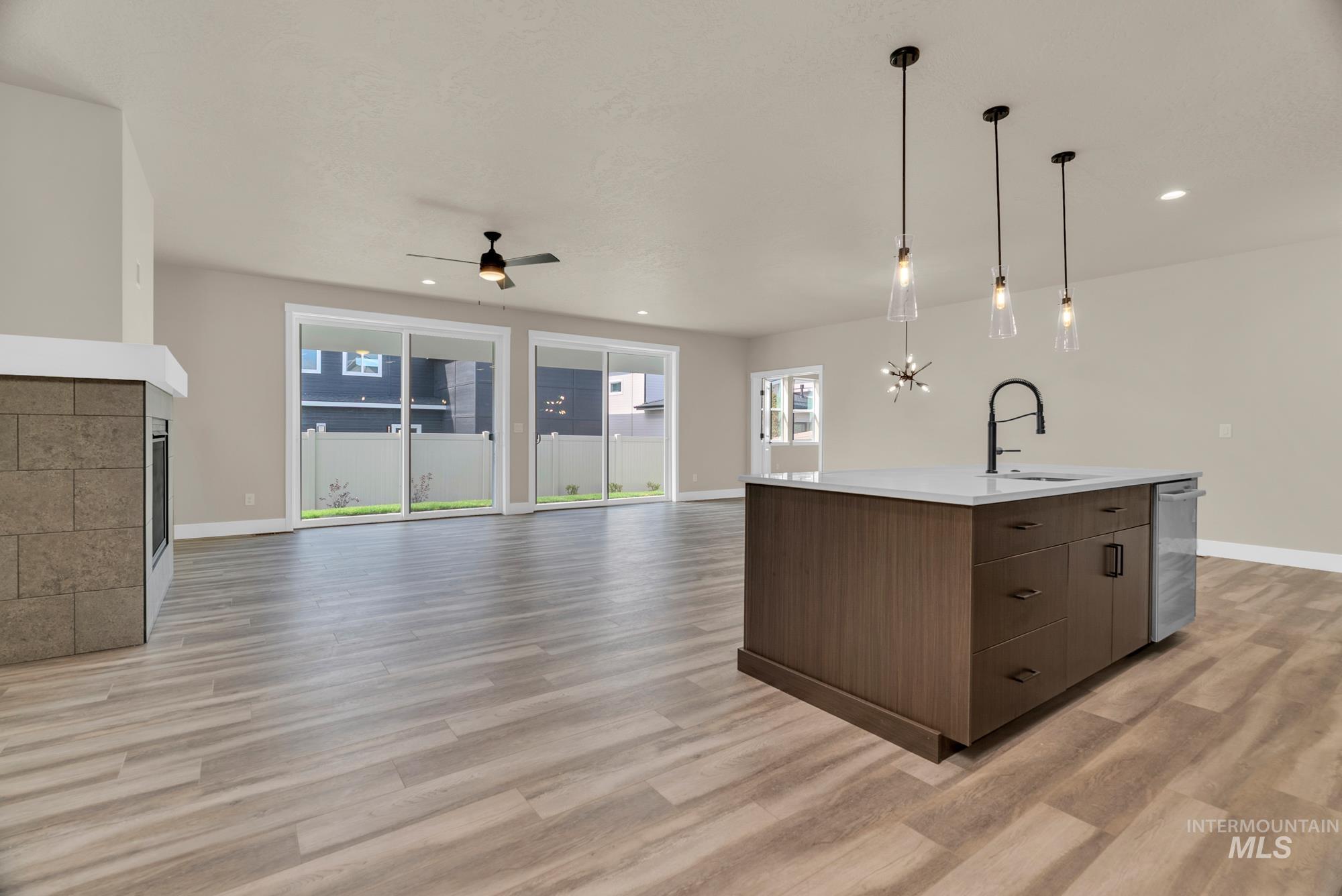 2848 West Jutland Street Meridian, ID 83642 - Photo 25 of 25 Kitchen with an island with sink, pendant lighting, open floor plan, a tile fireplace, and ceiling fan