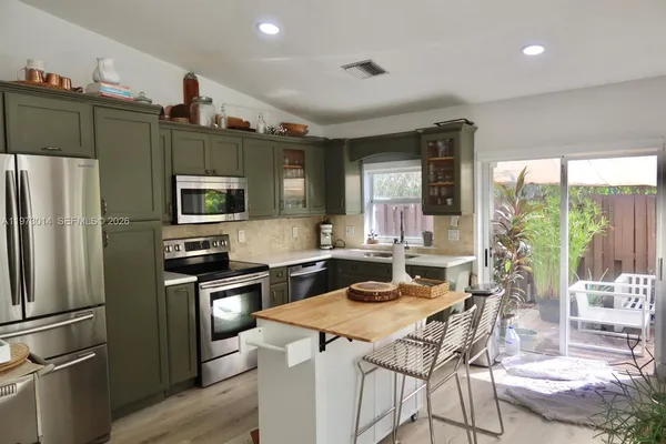 a kitchen with stainless steel appliances granite countertop a refrigerator a stove a sink dishwasher and white cabinets with wooden floor