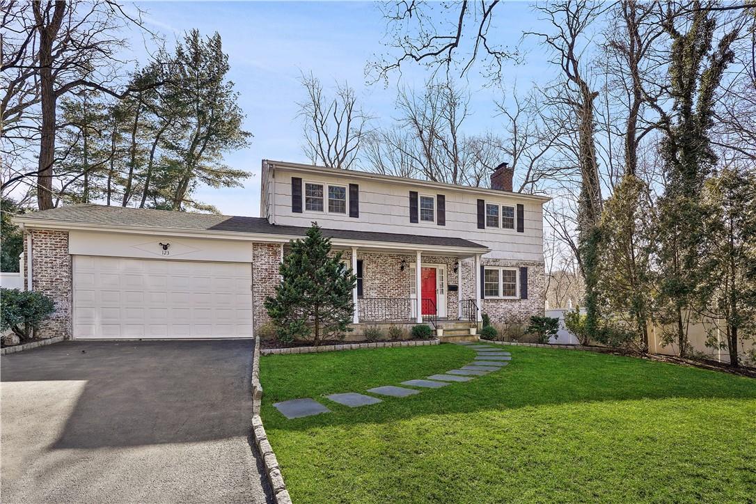 a front view of a house with a garden and trees