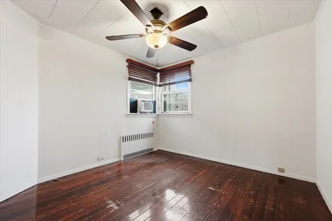 an empty room with wooden floor and ceiling fan