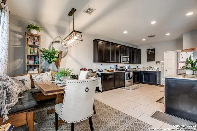 a kitchen with stainless steel appliances kitchen island granite countertop a sink dishwasher a stove a microwave oven with a dining table and chairs
