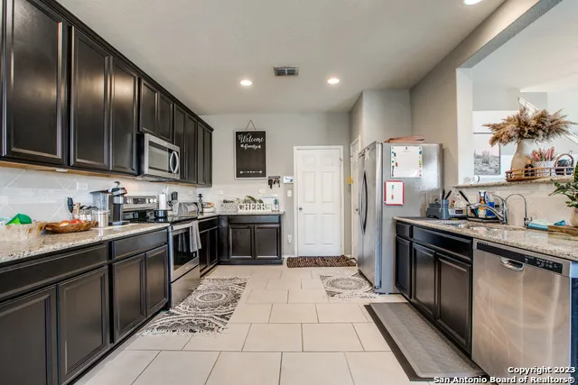 a large kitchen with stainless steel appliances granite countertop a stove top oven a sink dishwasher and a refrigerator