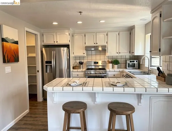a kitchen with stainless steel appliances granite countertop a sink a stove a refrigerator cabinets and chairs