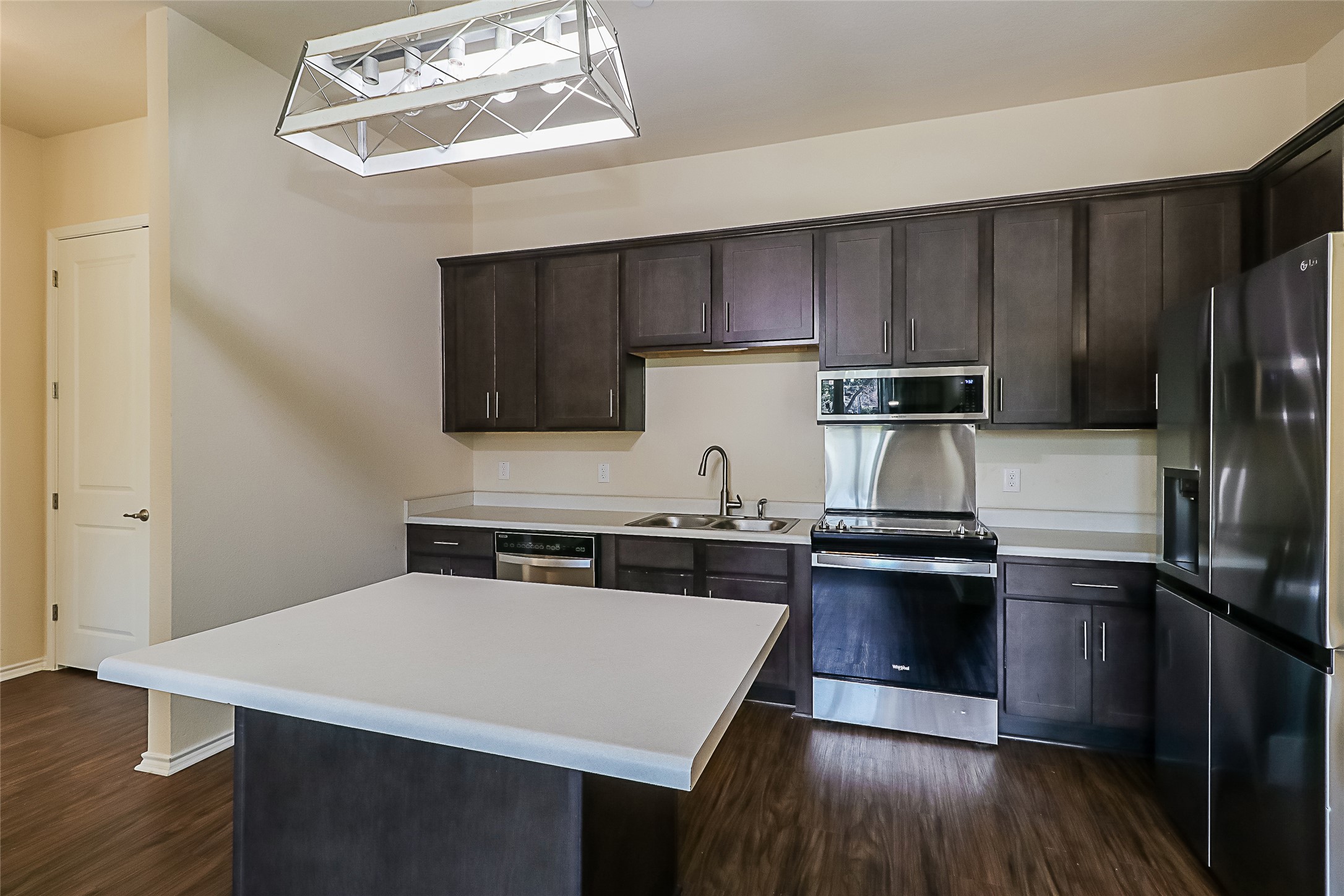 8601 West Gate Boulevard, Unit 7101 Austin, TX 78745 - Photo 7 of 16 Kitchen with stainless steel appliances, dark wood finish cabinetry, light countertops, a kitchen island, and dark wood-style flooring