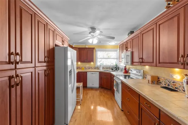 a kitchen with stainless steel appliances granite countertop a refrigerator a sink dishwasher a stove and a dining table with wooden floor