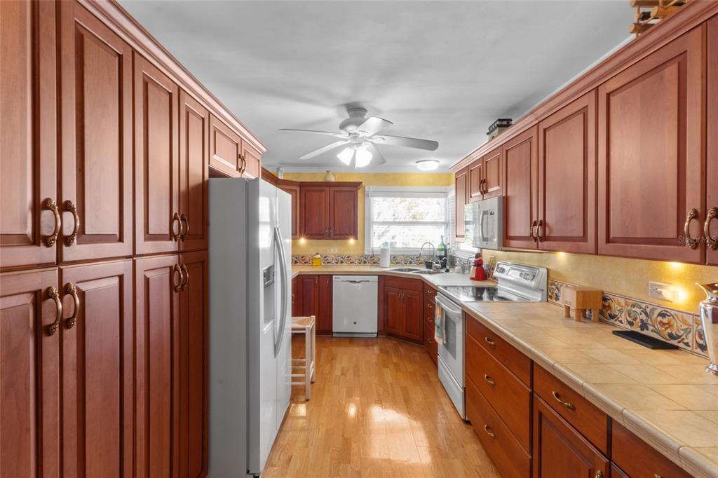420 Pensacola Road Venice, FL 34285 - Photo 9 of 40 a kitchen with stainless steel appliances granite countertop a refrigerator a sink dishwasher a stove and a dining table with wooden floor