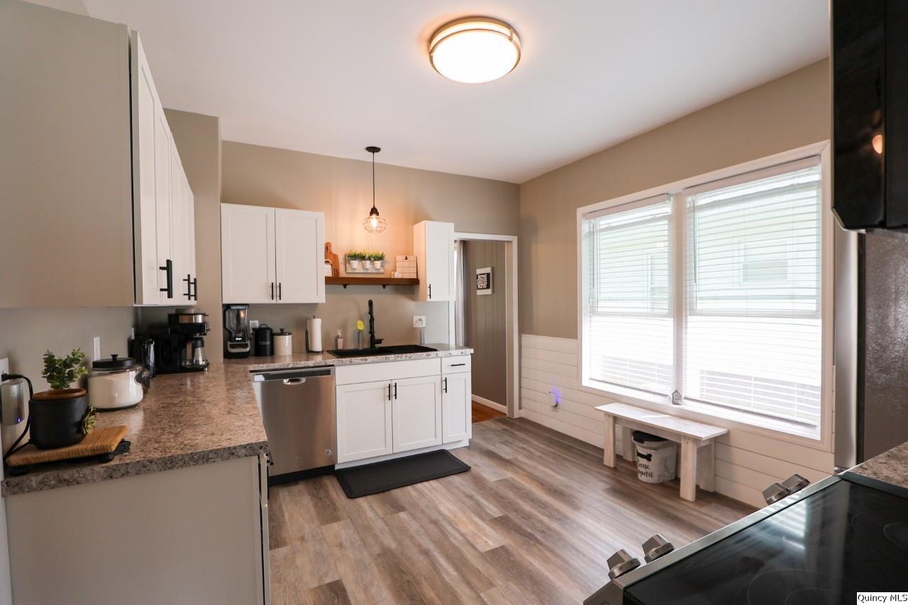 630 South 19th Street Quincy, IL 62301 - Photo 4 of 17 a kitchen with stainless steel appliances granite countertop a sink dishwasher a stove and white cabinets with wooden floor