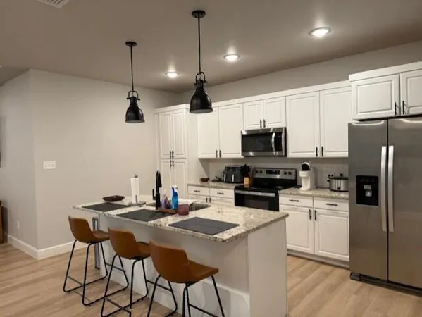 a kitchen with a dining table chairs refrigerator and microwave