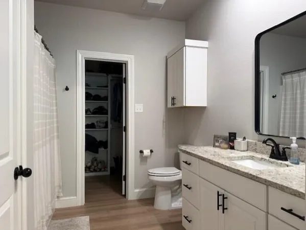 a bathroom with a granite countertop toilet a sink and a mirror