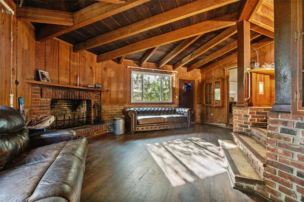 a view of a wooden house with a yard and sitting area
