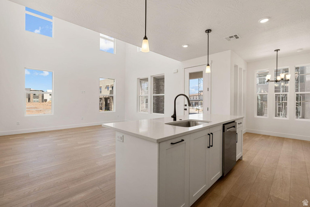 523 West Olive Lane St. George, UT 84790 - Photo 47 of 47 Kitchen with light wood-style flooring, open floor plan, white cabinetry, a kitchen island with sink, and a high ceiling