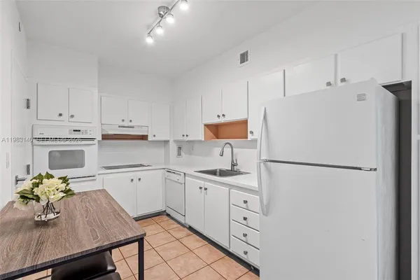 a kitchen with kitchen island granite countertop a sink a stove and cabinets