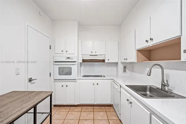a kitchen with stainless steel appliances a sink dishwasher a refrigerator a stove and white cabinets with wooden floor