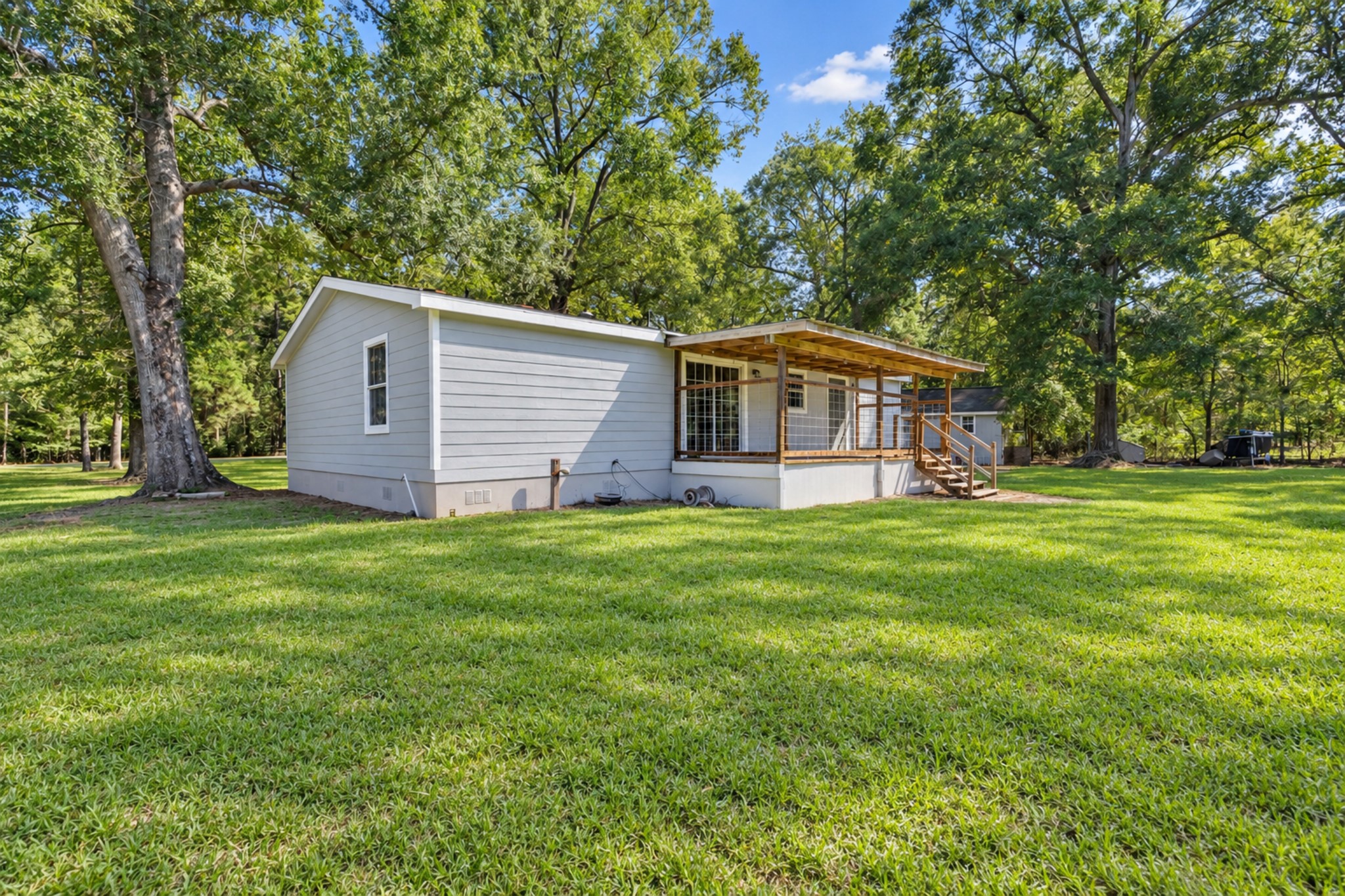 2009 Holder Rambo Drive Huffman, TX 77336 - Photo 7 of 31 Charming home with a spacious backyard surrounded by mature trees, featuring a cozy porch perfect for relaxing outdoors.