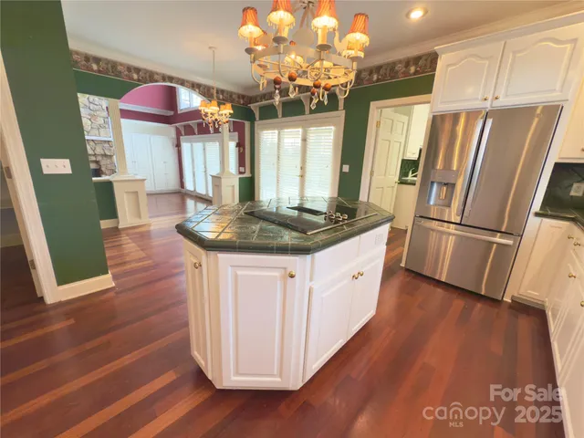 a kitchen with stainless steel appliances granite countertop a refrigerator a stove a sink dishwasher and a refrigerator with wooden floor