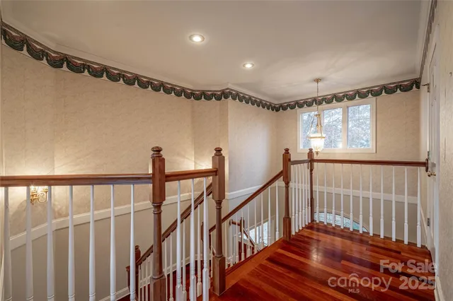 a view of a hallway with wooden floor and chandelier