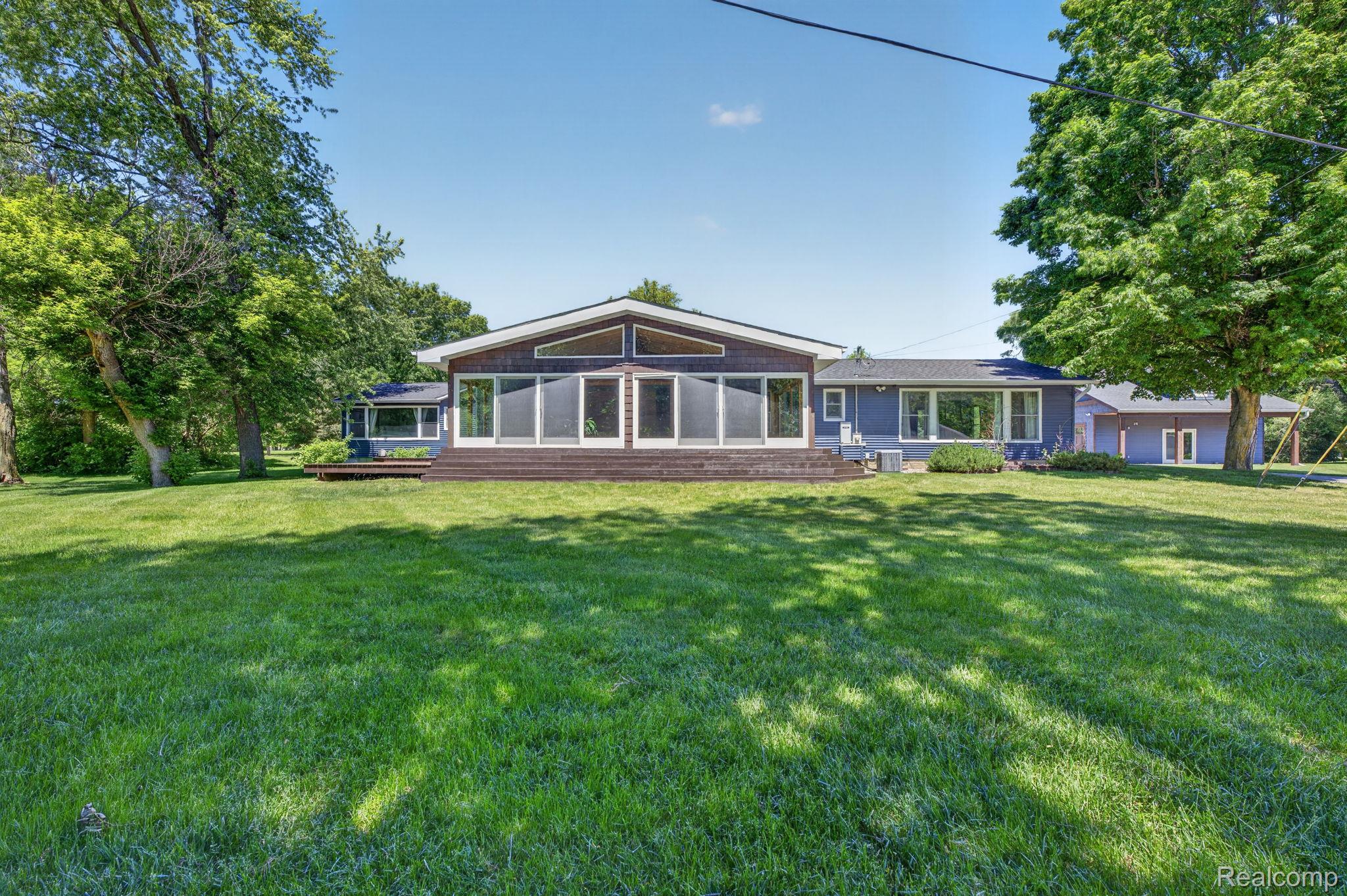 9353 Hill Road Swartz Creek, MI 48473 - Photo 88 of 98 Expansive green lawn presenting a multi-level residence with a wood-sided upper section and a blue lower section