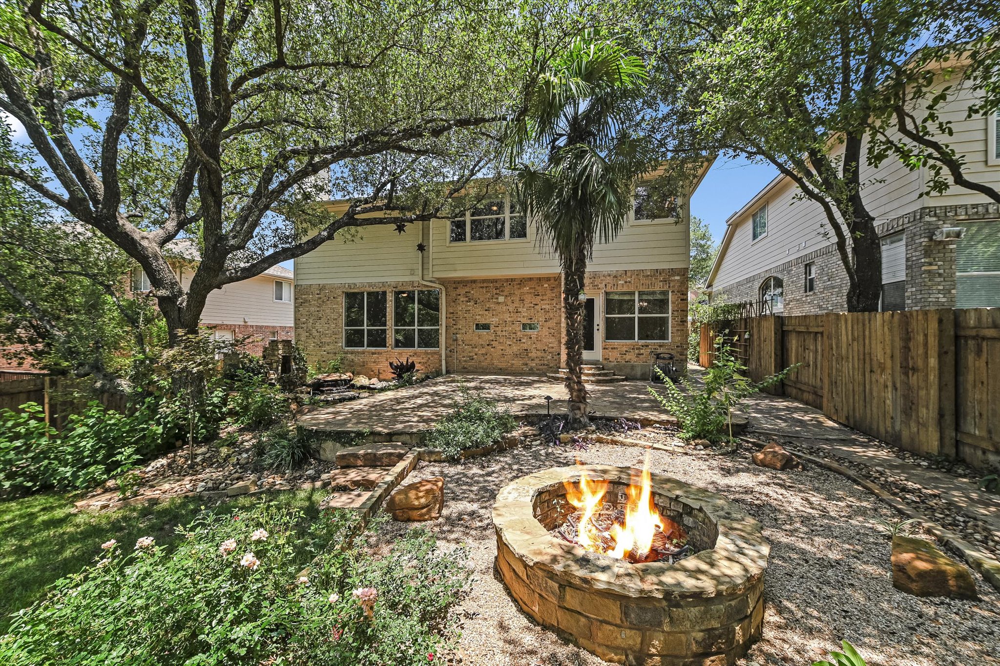 2849 Grimes Ranch Road Austin, TX 78732 - Photo 30 of 31 A private backyard oasis features a cozy stone fire pit, ideal for evening gatherings under mature trees.