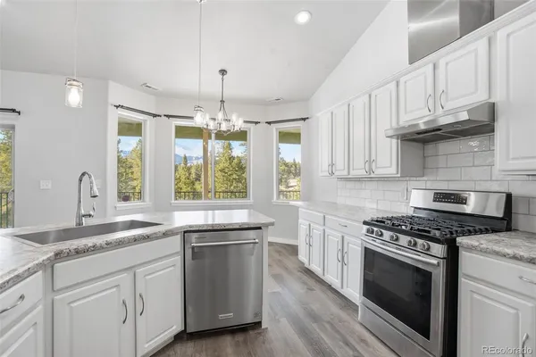 a kitchen with granite countertop a sink cabinets stainless steel appliances and a window
