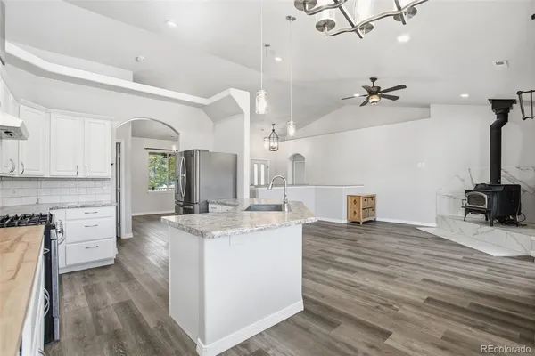 a kitchen with kitchen island a stove a sink and a refrigerator with wooden floor