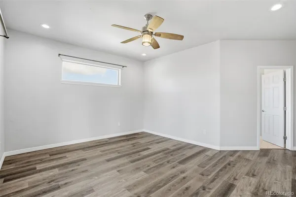 a view of a room with wooden floor and a ceiling fan