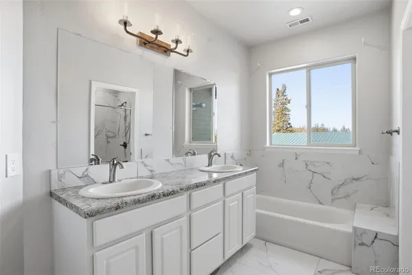 a bathroom with a granite countertop sink mirror and a bathtub