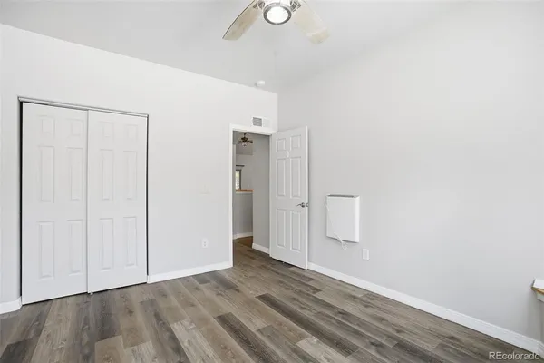 a view of an empty room with wooden floor and closet