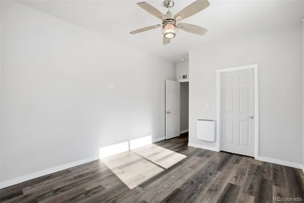 an empty room with wooden floor closet fan and windows