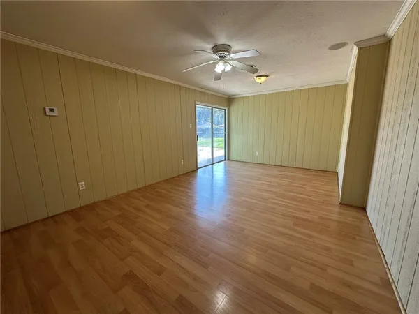 a view of an empty room with wooden floor and a chandelier