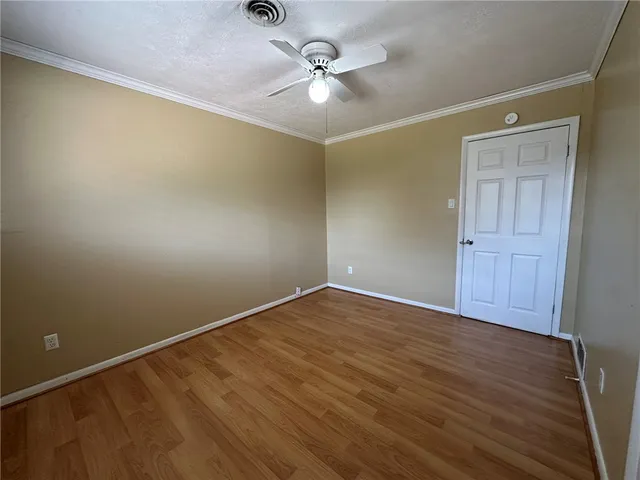 an empty room with a ceiling fan and wooden floor