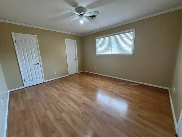 a view of empty room with wooden floor and fan