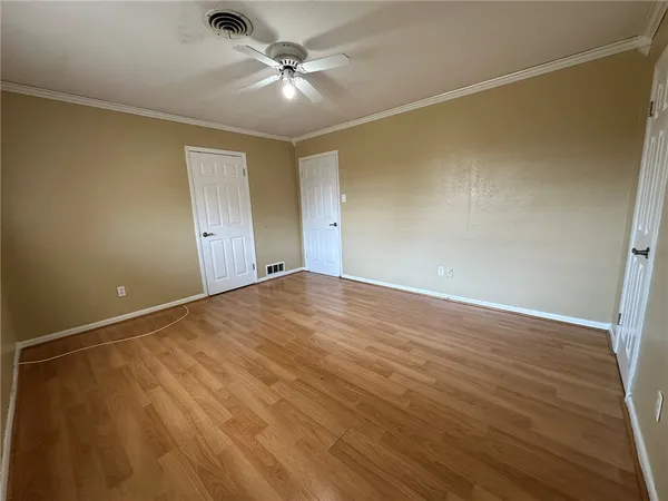 an empty room with wooden floor and fan