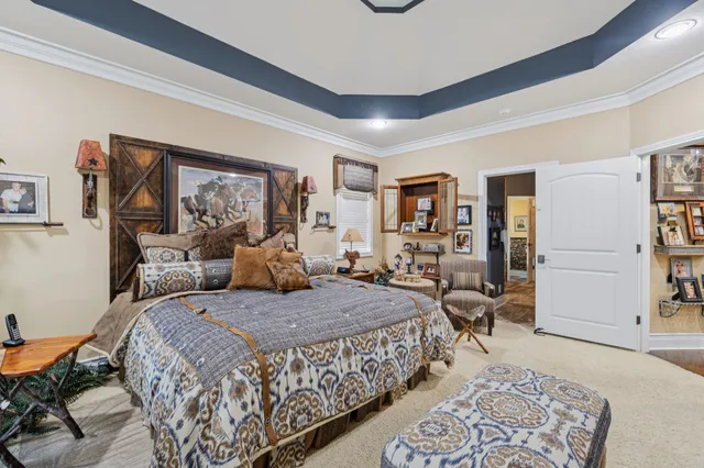 a bedroom with a large bed a chandelier and dresser