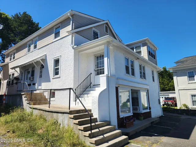 a view of a white building among the street with potted plants