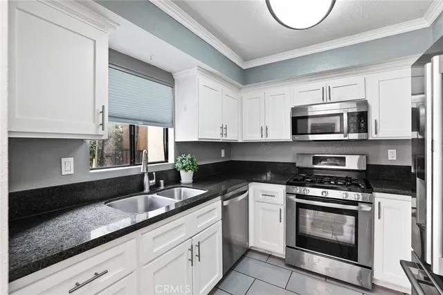 a kitchen with granite countertop a sink a stove top oven and cabinetry