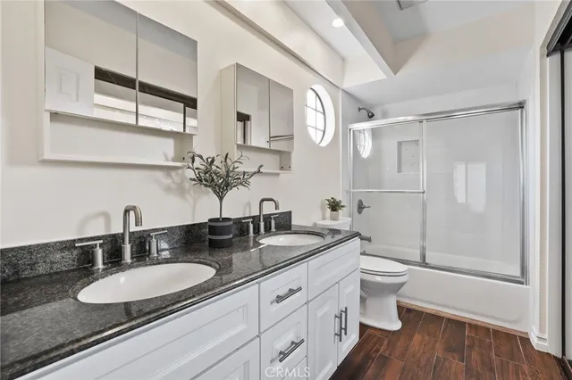 a bathroom with a granite countertop double vanity sink a mirror and a shower