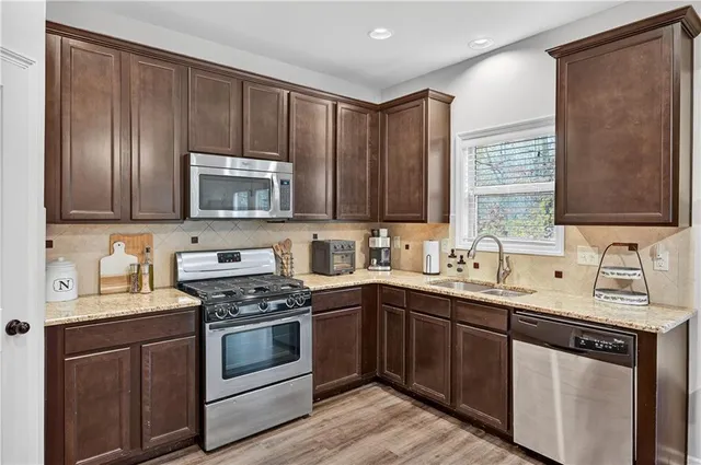 a kitchen with stainless steel appliances granite countertop a sink stove microwave and refrigerator