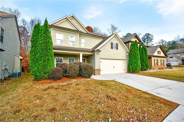 a view of a house with a small yard and large tree