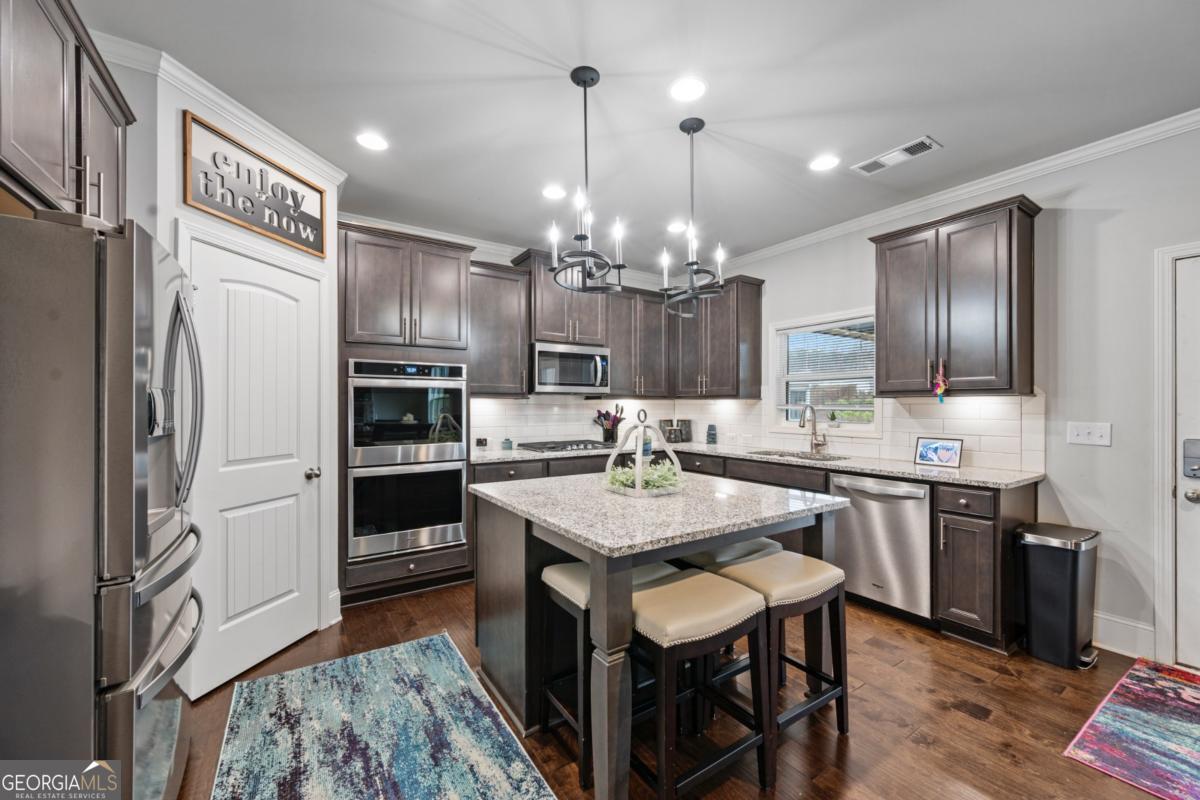 6780 Rambling Vale Dawsonville, GA 30534 - Photo 11 of 52 a kitchen with kitchen island granite countertop stainless steel appliances a sink stove and refrigerator