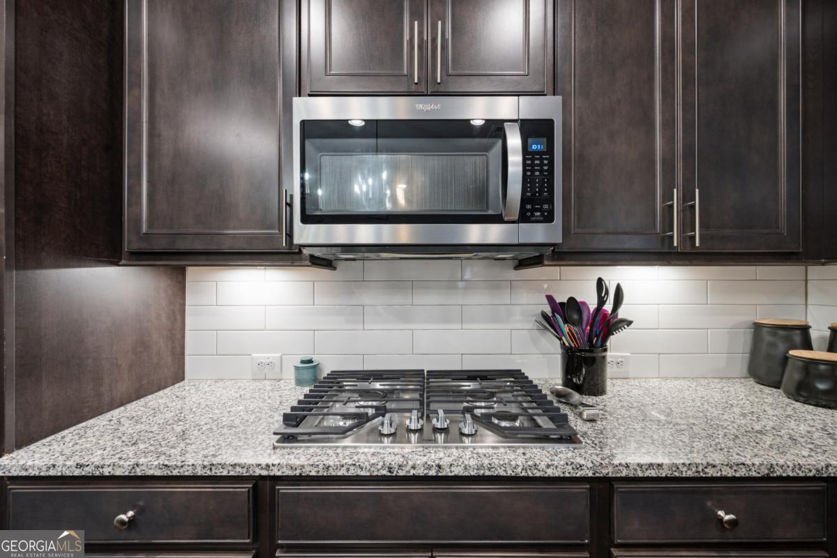 6780 Rambling Vale Dawsonville, GA 30534 - Photo 12 of 52 a kitchen with granite countertop a stove a microwave a sink and cabinets