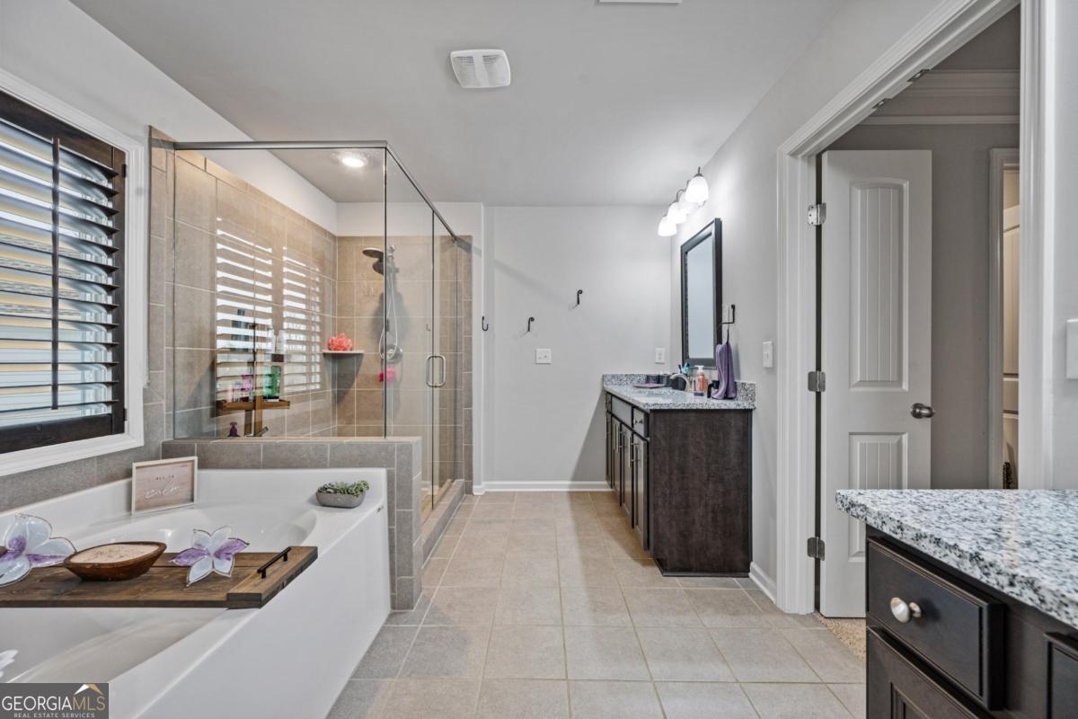 6780 Rambling Vale Dawsonville, GA 30534 - Photo 34 of 52 a bathroom with a granite countertop sink a large mirror and a bathtub