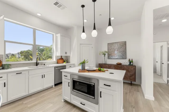 a kitchen that has a stove a sink a window and wooden floor