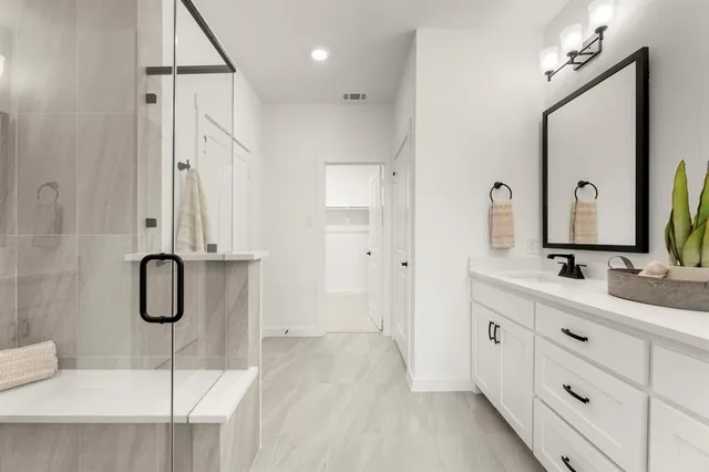 a bathroom with a granite countertop sink two mirror and shower