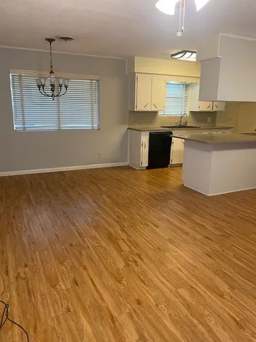 a view of a kitchen with kitchen island stainless steel appliances a sink cabinets and wooden floor