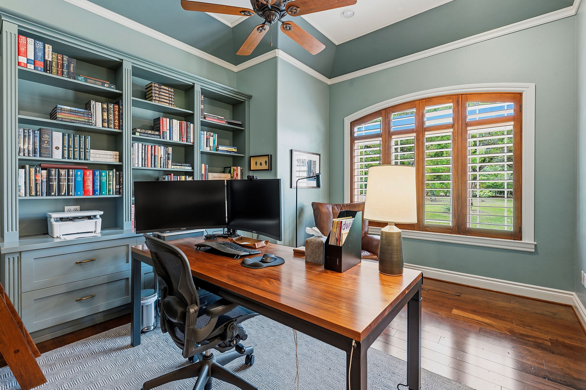 8121 Bluff Trail Austin, TX 78737 - Photo 22 of 40 A refined home office showcases custom built-in shelving, rich wood flooring, and a coffered ceiling.