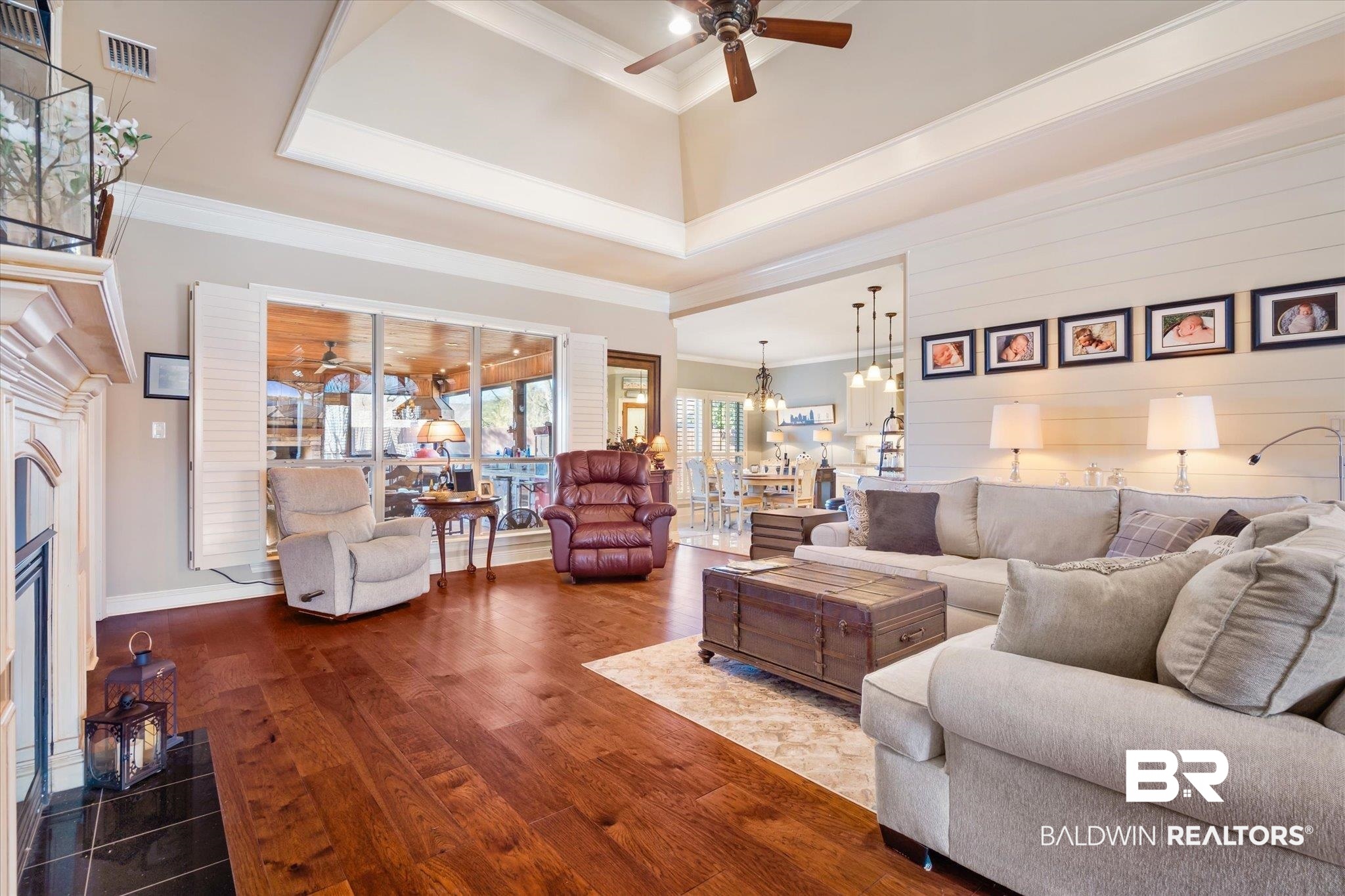 5683 Spring Landing Drive Theodore, AL 36582 - Photo 8 of 49 Living room featuring wooden walls, ceiling fan with notable chandelier, ornamental molding, dark hardwood / wood-style floors, and a tray ceiling