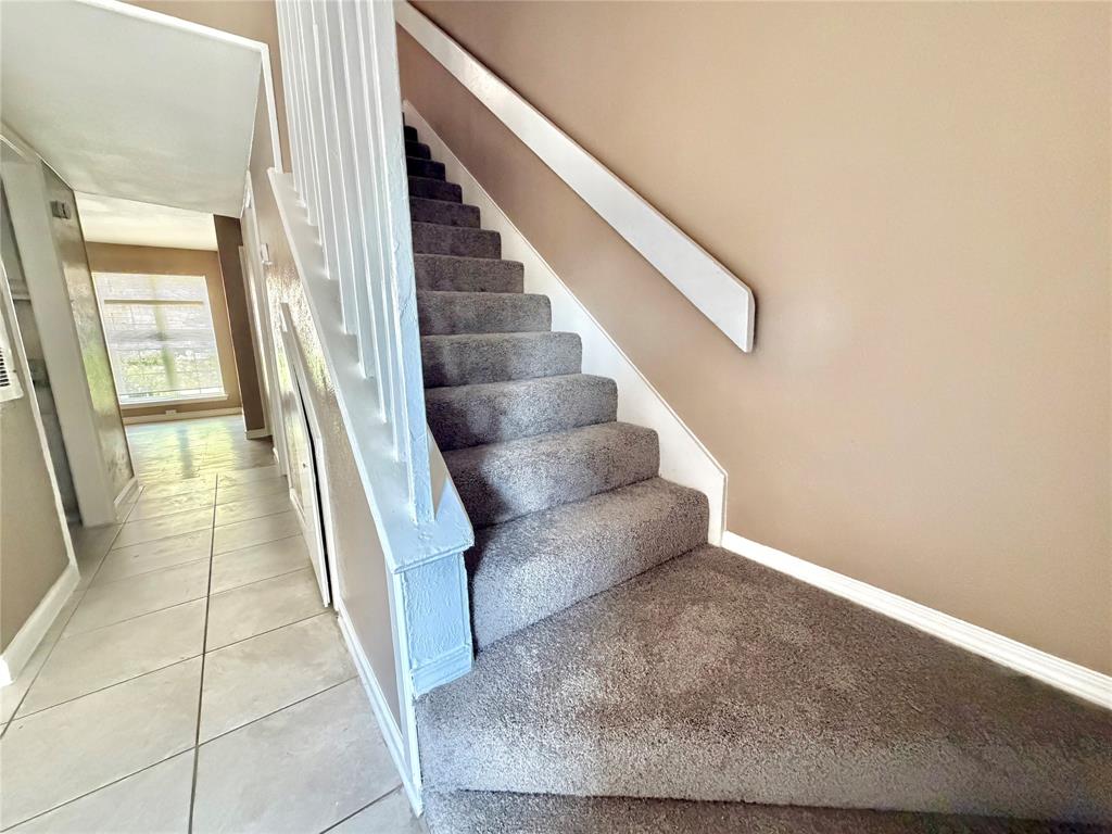8001 Rothington Road, Unit 33 Dallas, TX 75227 - Photo 9 of 15 Carpeted staircase with white balusters and handrail, featuring neutral wall paint and white trim
