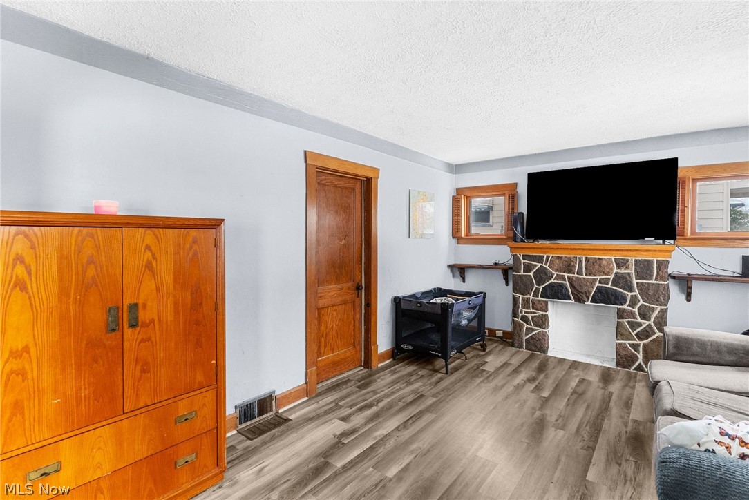 464 Elm Street Struthers, OH 44471 - Photo 6 of 22 Living room with wood finished floors, a stone fireplace, and a textured ceiling
